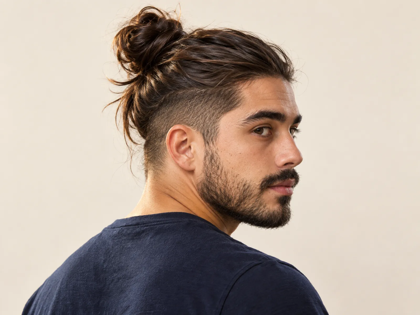 Hombre chileno de tres cuartos con man bun en la coronilla y costados cortos